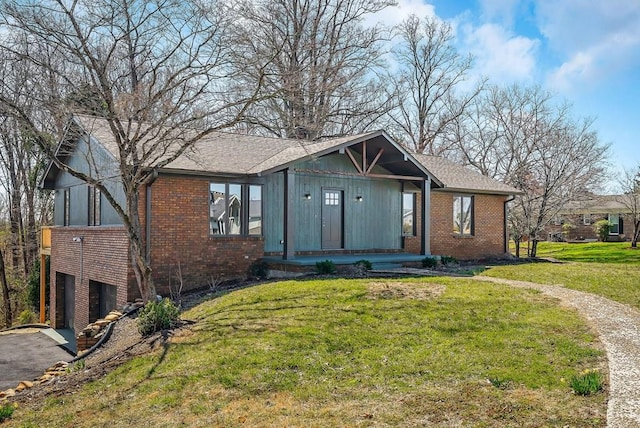 view of front of property featuring brick siding, a garage, driveway, and a front lawn