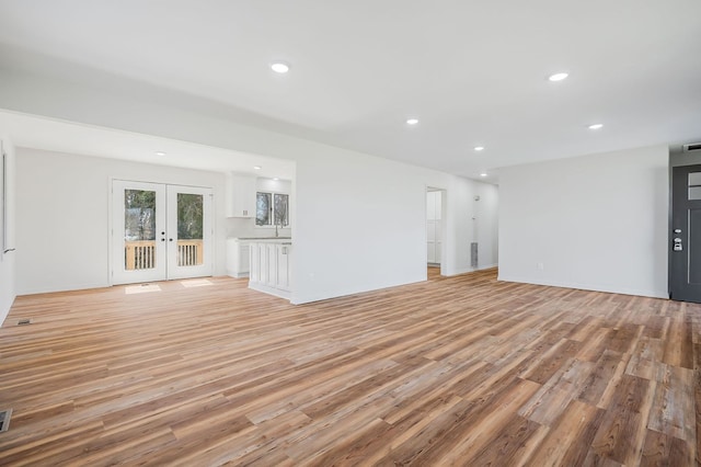 unfurnished living room with recessed lighting, french doors, and light wood finished floors