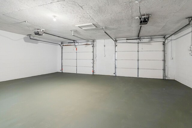 garage featuring concrete block wall and a garage door opener