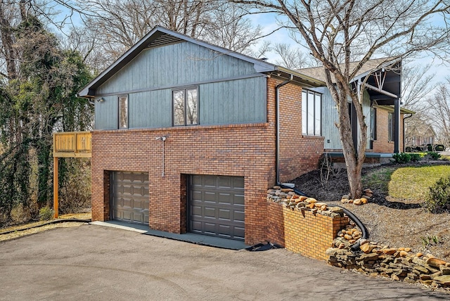 view of home's exterior with a garage, brick siding, and driveway