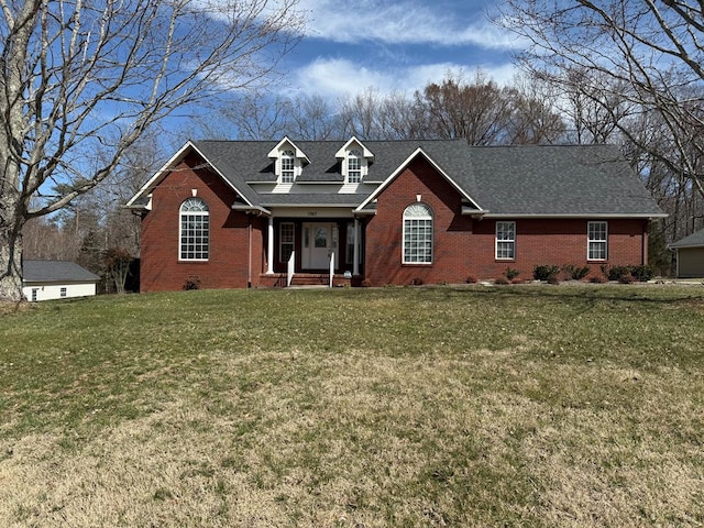 view of front facade with a front yard, brick siding, and roof with shingles