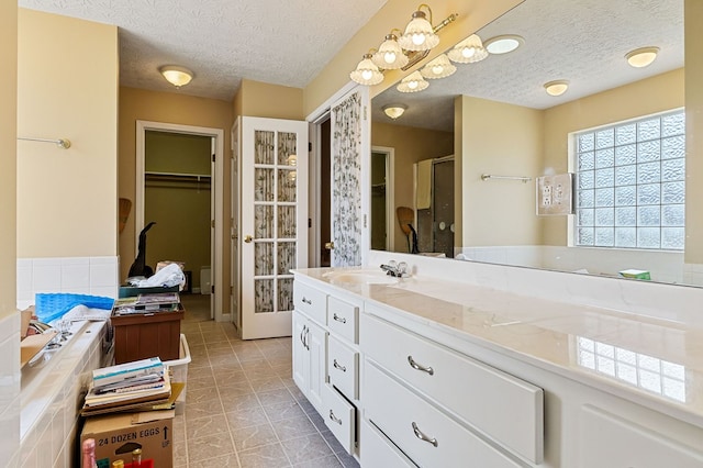 bathroom featuring a spacious closet, a stall shower, vanity, a textured ceiling, and tile patterned flooring