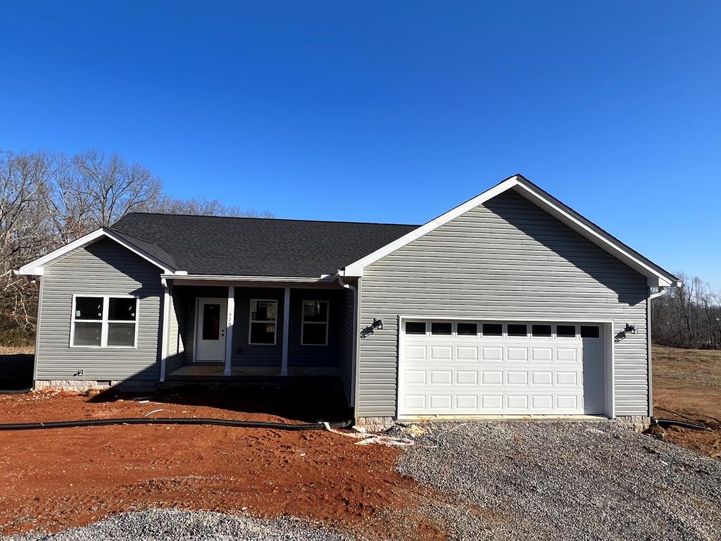 single story home featuring an attached garage, covered porch, crawl space, and gravel driveway