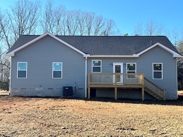 back of property with crawl space, a deck, cooling unit, and roof with shingles