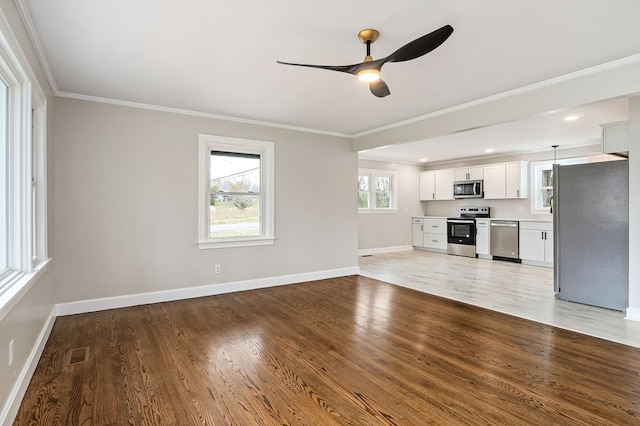 unfurnished living room with light wood finished floors, baseboards, visible vents, a ceiling fan, and crown molding