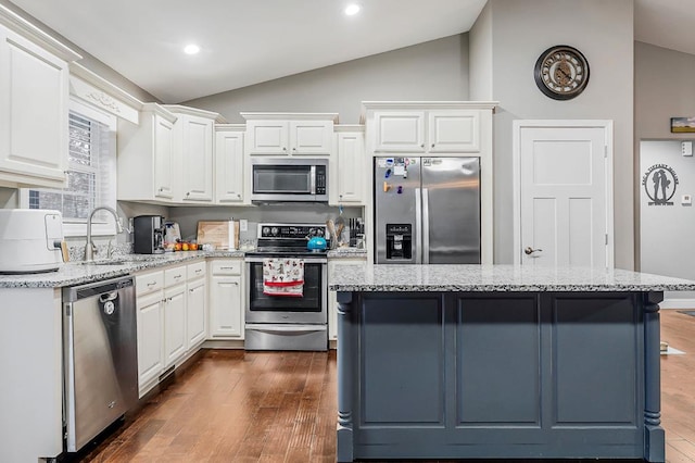 kitchen with a kitchen island, appliances with stainless steel finishes, light stone counters, and a sink