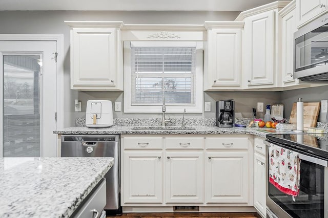 kitchen with stainless steel appliances, a sink, visible vents, and white cabinets