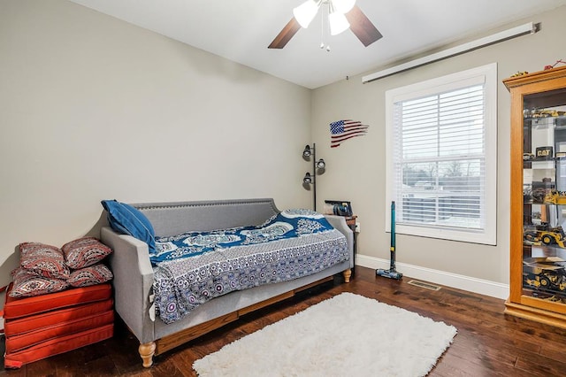 bedroom with a ceiling fan, dark wood-style flooring, visible vents, and baseboards