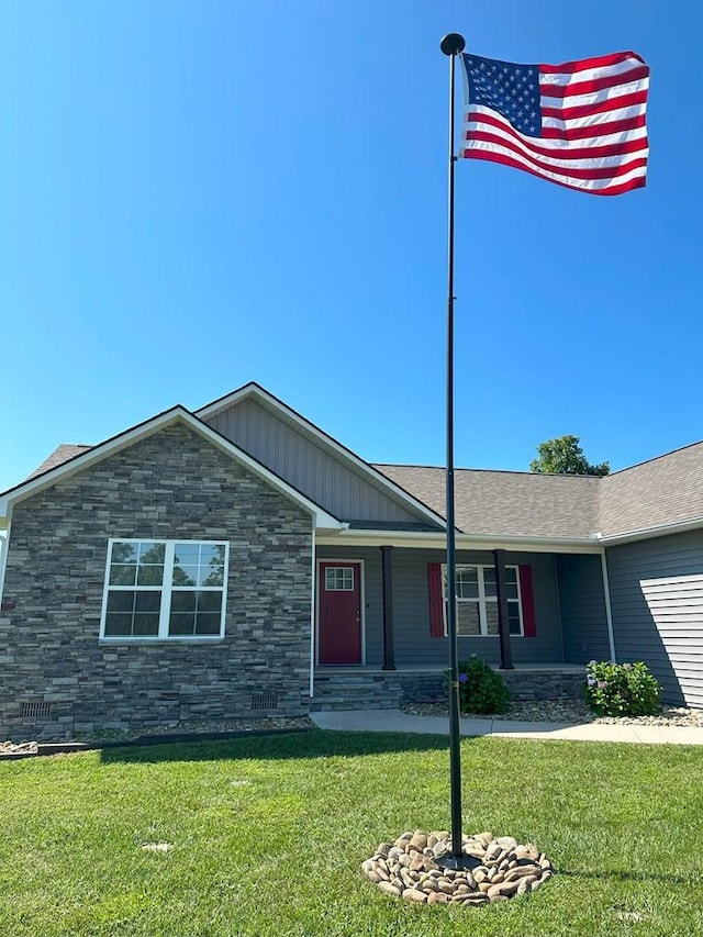 ranch-style home featuring a shingled roof, stone siding, and a front lawn