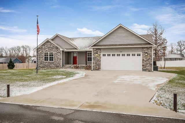 single story home featuring driveway, stone siding, an attached garage, and fence