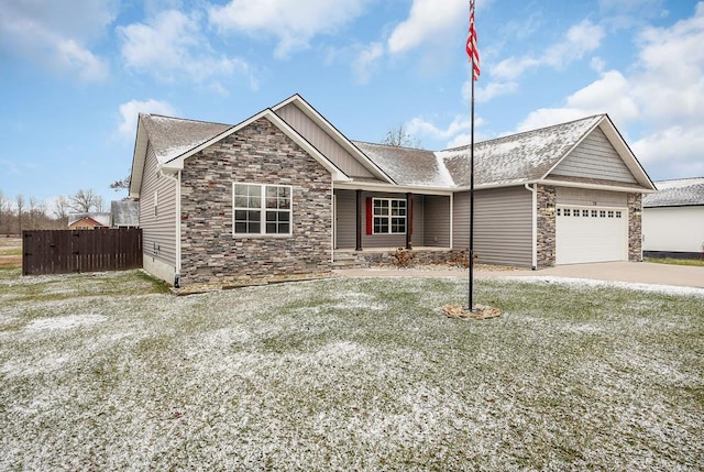 view of front of property featuring concrete driveway, fence, a garage, stone siding, and a front lawn