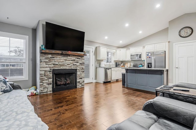 living area featuring a fireplace, vaulted ceiling, dark wood-type flooring, and recessed lighting