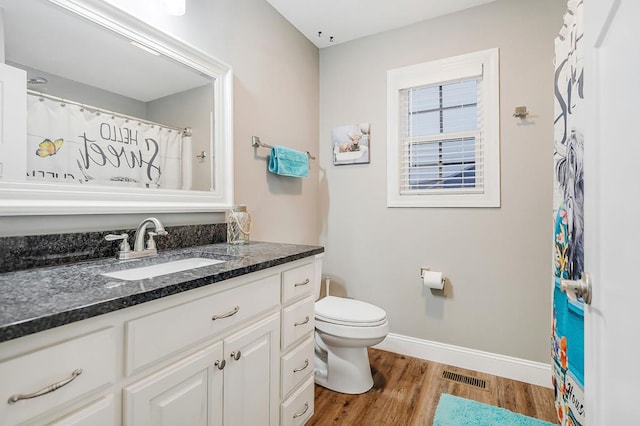 bathroom featuring visible vents, toilet, vanity, wood finished floors, and baseboards