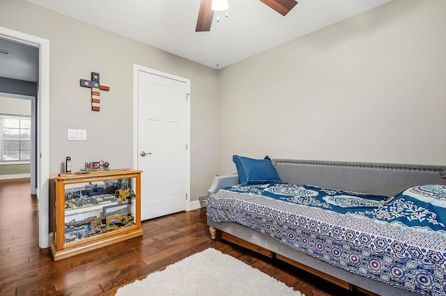 bedroom with dark wood-type flooring, a ceiling fan, and baseboards