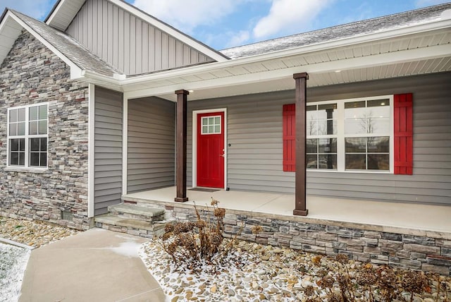 doorway to property with stone siding, a porch, and board and batten siding