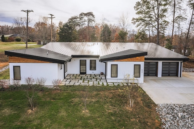 view of front of house with a garage, covered porch, concrete driveway, stucco siding, and a front lawn