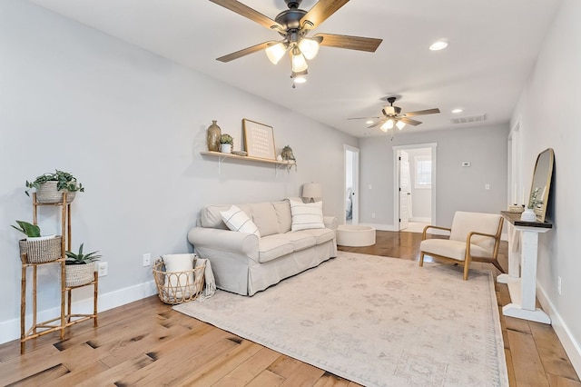 living room with recessed lighting, visible vents, baseboards, and wood finished floors