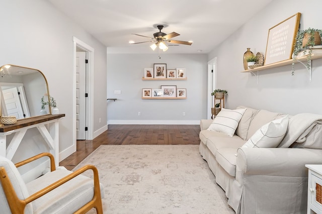 living room with baseboards, ceiling fan, and light wood finished floors