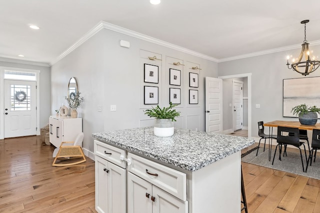 kitchen with crown molding, light wood-type flooring, a kitchen island, and white cabinets