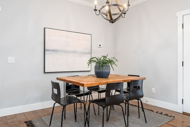 dining space featuring a chandelier, crown molding, baseboards, and wood finished floors