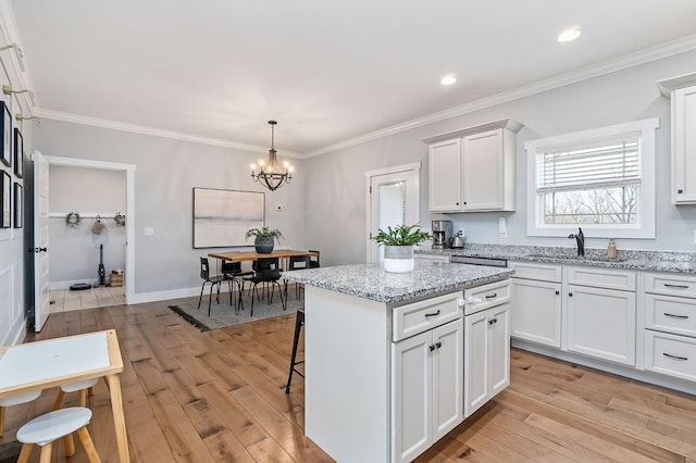 kitchen featuring white cabinets, a sink, and a center island