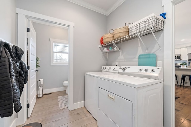 laundry room with laundry area, separate washer and dryer, baseboards, ornamental molding, and wood tiled floor