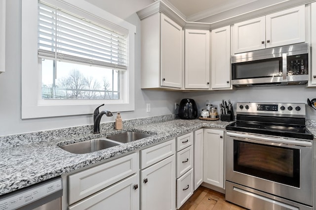 kitchen featuring appliances with stainless steel finishes, light wood-style floors, white cabinetry, a sink, and light stone countertops