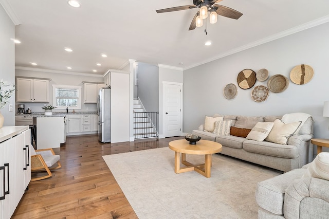 living room featuring light wood finished floors, recessed lighting, stairway, and ornamental molding