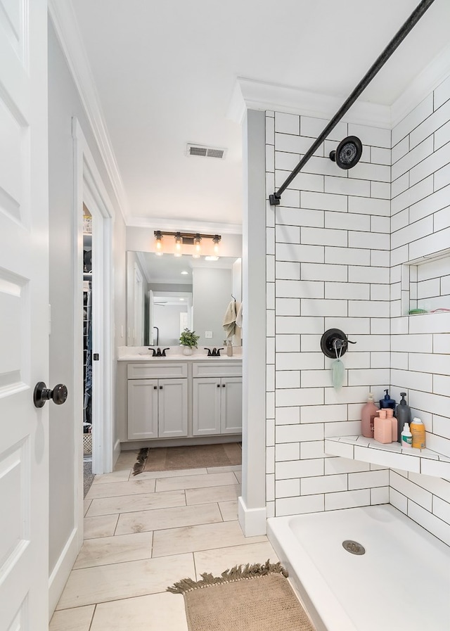 full bathroom with double vanity, visible vents, crown molding, a shower stall, and a sink