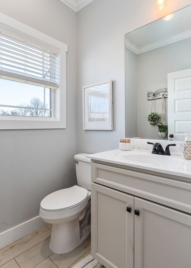 half bath with baseboards, toilet, ornamental molding, wood finished floors, and vanity