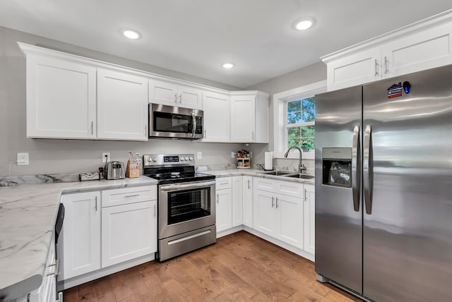 kitchen featuring white cabinetry, stainless steel appliances, a sink, and wood finished floors