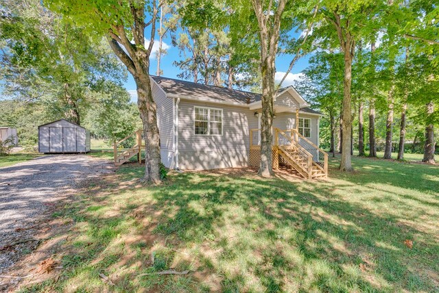 view of front of house featuring a shed, stairs, a front lawn, and an outdoor structure