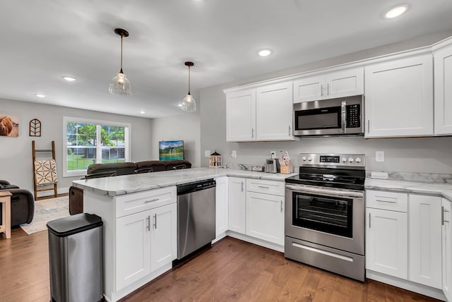 kitchen featuring stainless steel appliances, a peninsula, white cabinetry, open floor plan, and pendant lighting