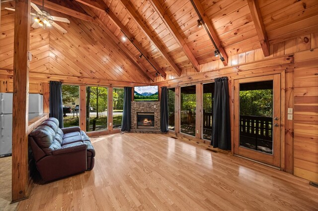 unfurnished living room with beam ceiling, light wood-style floors, wood ceiling, and wooden walls