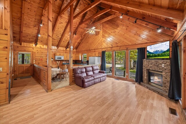 living area with a fireplace, visible vents, light wood-style floors, wood ceiling, and wooden walls