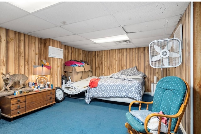 bedroom featuring a drop ceiling, wood walls, carpet, and visible vents