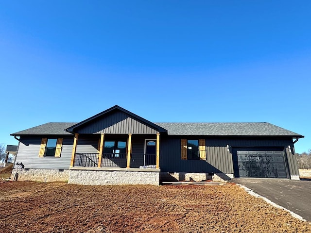 view of front facade with roof with shingles, covered porch, an attached garage, crawl space, and driveway