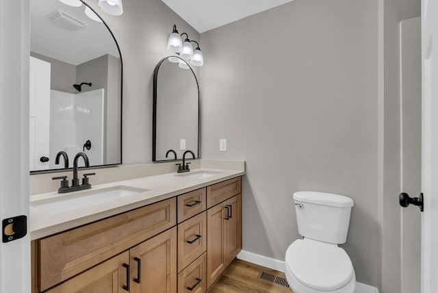 bathroom featuring visible vents, a sink, toilet, and double vanity