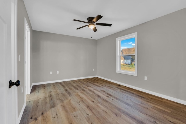 spare room with a ceiling fan, light wood-style flooring, and baseboards