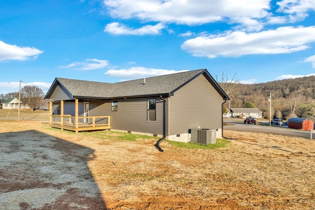 exterior space with roof with shingles, crawl space, cooling unit, and a wooden deck