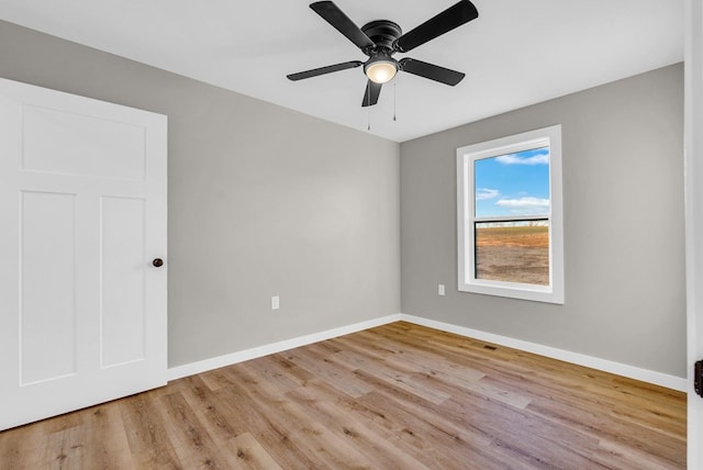 empty room with light wood-type flooring, ceiling fan, and baseboards