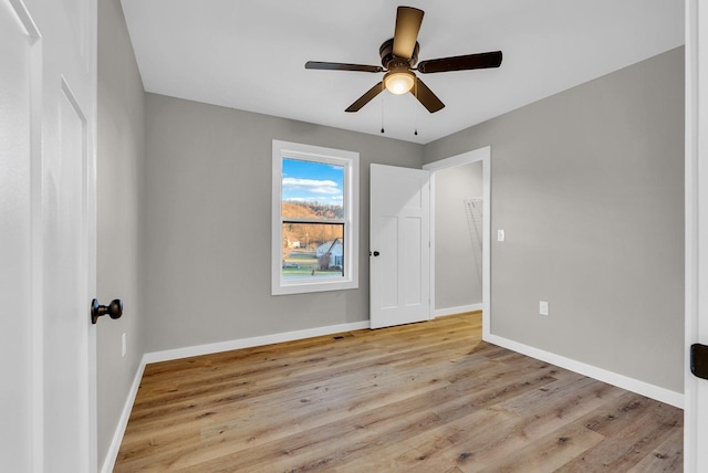 unfurnished bedroom featuring light wood finished floors, baseboards, and a ceiling fan