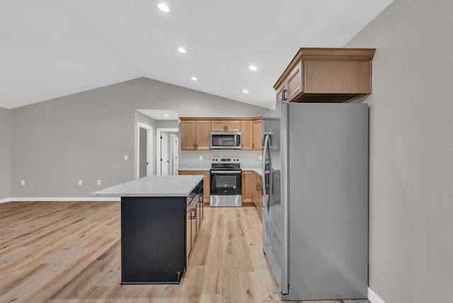 kitchen featuring lofted ceiling, light stone counters, stainless steel appliances, a kitchen island, and light wood-type flooring