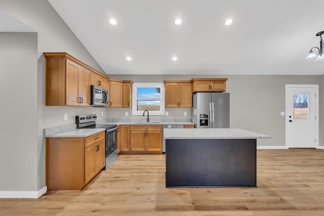 kitchen with light wood finished floors, appliances with stainless steel finishes, decorative light fixtures, a center island, and a sink