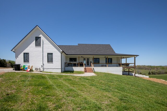 back of property with brick siding, a porch, a ceiling fan, and a yard