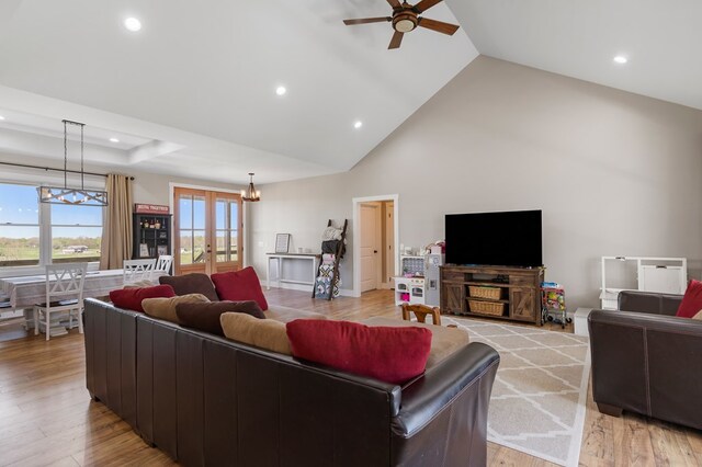 living room with ceiling fan with notable chandelier, french doors, light wood-type flooring, high vaulted ceiling, and recessed lighting