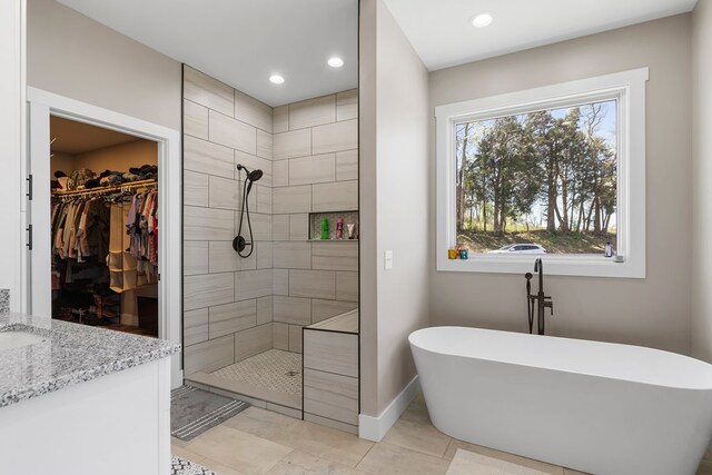 full bath featuring a walk in closet, recessed lighting, a freestanding tub, baseboards, and walk in shower