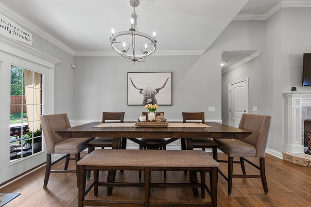 dining room featuring baseboards, dark wood-style floors, crown molding, a notable chandelier, and a high end fireplace