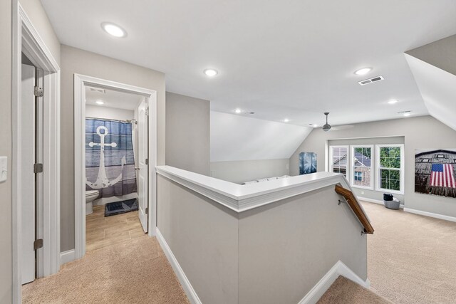 hall featuring vaulted ceiling, visible vents, an upstairs landing, and light colored carpet