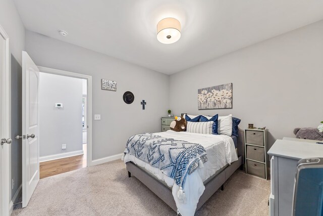 bedroom featuring light carpet and baseboards